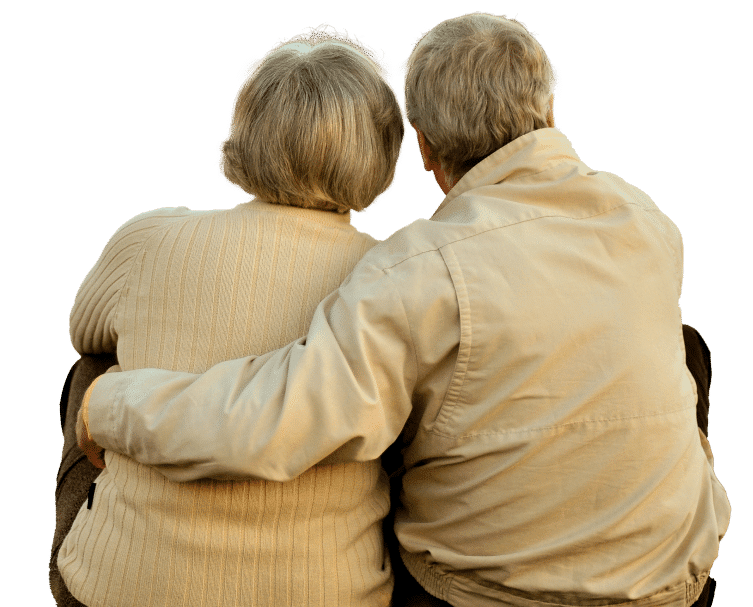 An elderly couple sits closely together, embracing and gazing towards the horizon, sharing a moment of love and companionship.