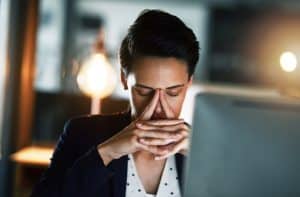 Shot of a young businesswoman looking stressed out while working late in an office.