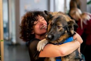 the pooch is already in the arms of his owner he is happy to be next to her in anticipation of something tasty