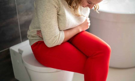 woman siting on toilet while having diarrhea