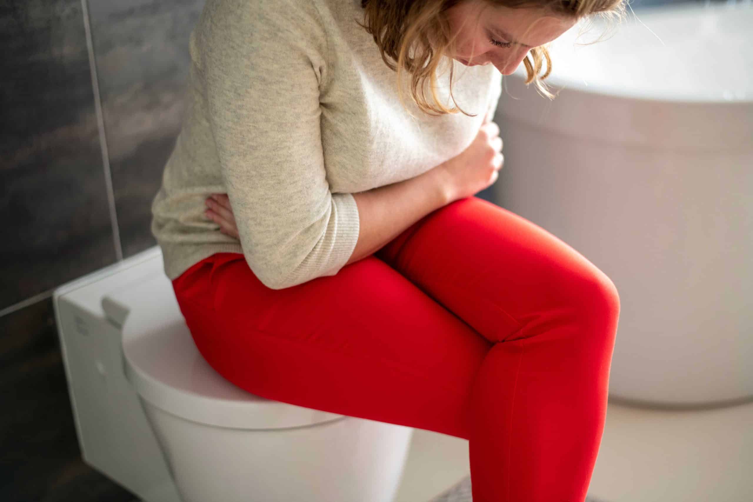 woman siting on toilet while having diarrhea
