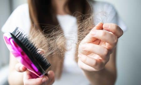 woman getting hair on her hairbrush