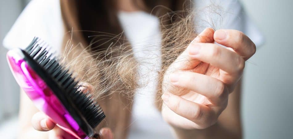 woman getting hair on her hairbrush