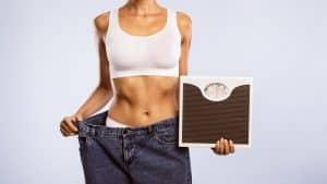 Woman Holding Scales Pulling Her Old Large Jeans