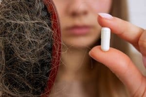 woman holding supplement for hair loss