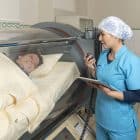 A nurse talking with a patient inside a cylindrical hyperbaric treatment machine