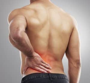 A shirtless person facing away holds their lower back, with a red area indicating pain or discomfort, highlighting common areas targeted for relief in CBD vs. THC discussions.