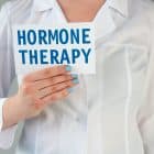white coat doctor holding a card with "hormone therapy " written on it