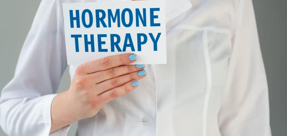 white coat doctor holding a card with "hormone therapy " written on it